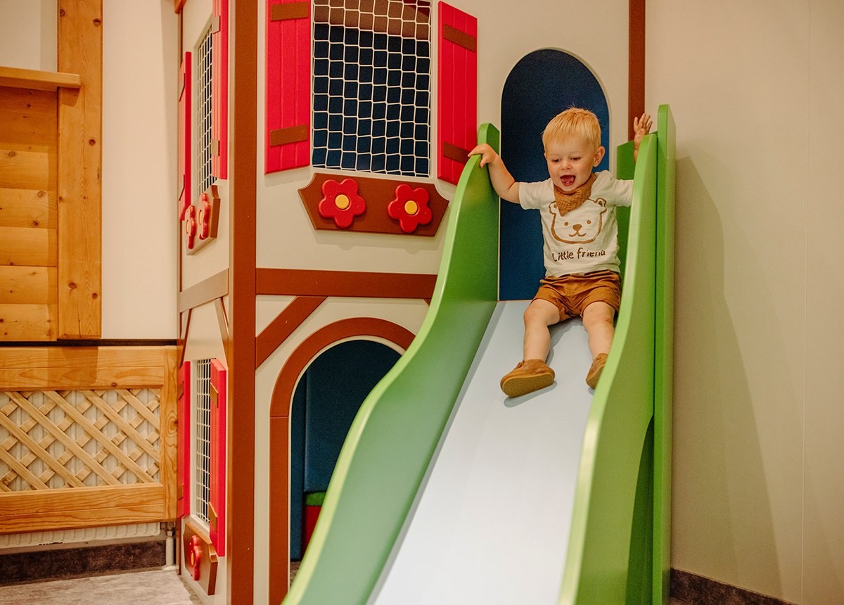 Kind auf Rutsche im Spielzimmer