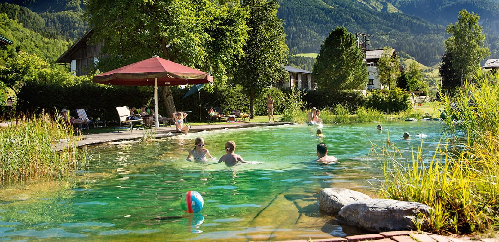 Kinder schwimmen und spielen im Naturschwimmteich beim Familienurlaub in Lerchs Landhotel
